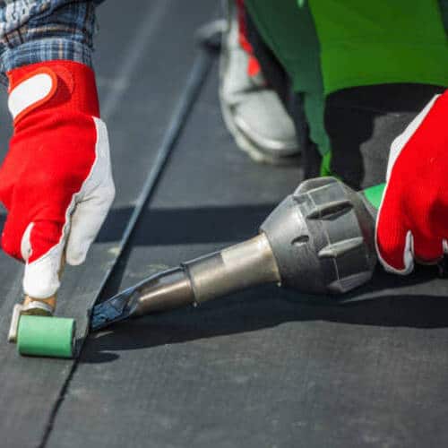 Contractor Covering Building Roof with EPDM Vinyl Rubber Material Close Up Photo.